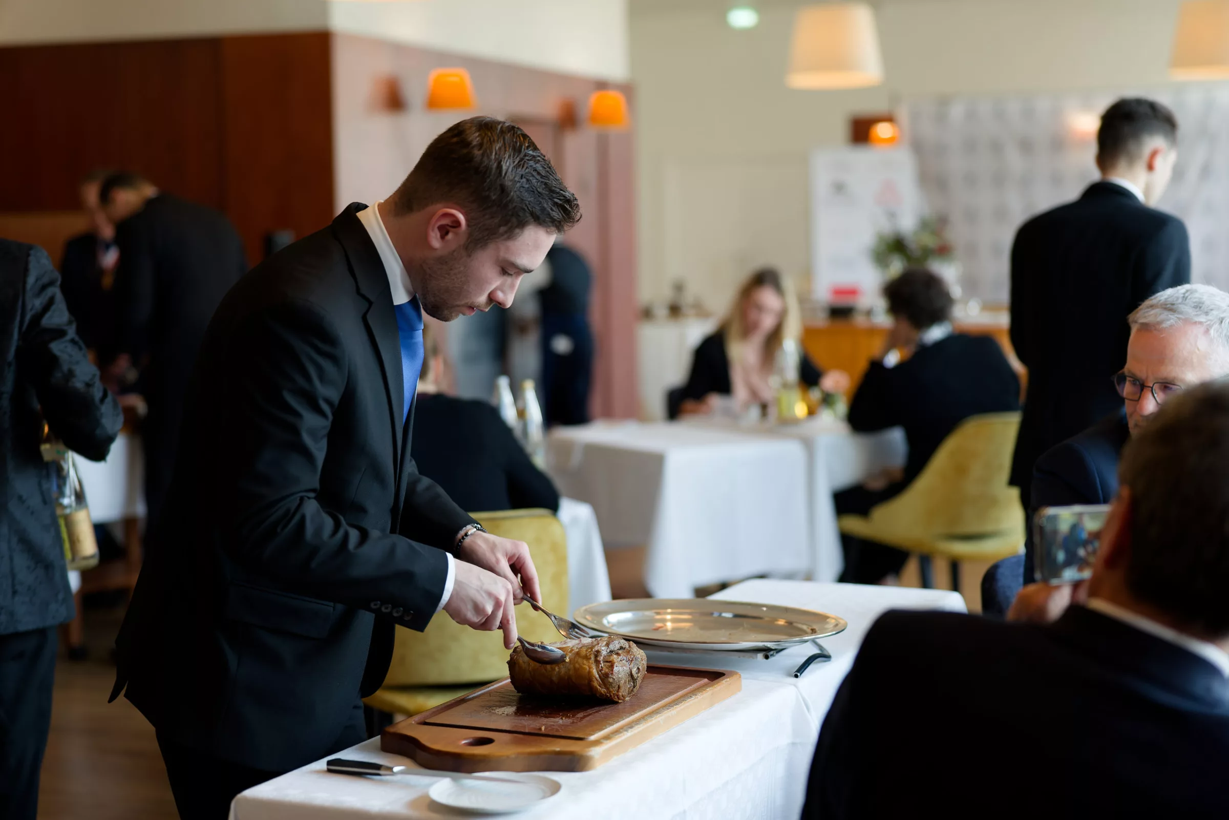 Découpe d'une viande sur table par un jeune professionnel scruté par les professionnels juges.